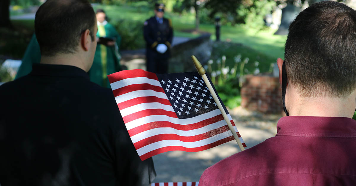 person holding american flag during sept 11 prayer service at saint vincent college