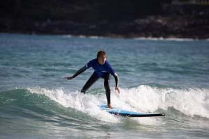 A person surfing on a blue surfboard while riding a wave in the ocean.