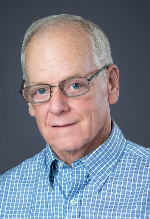 Headshot of an older man wearing glasses and a blue checkered shirt.